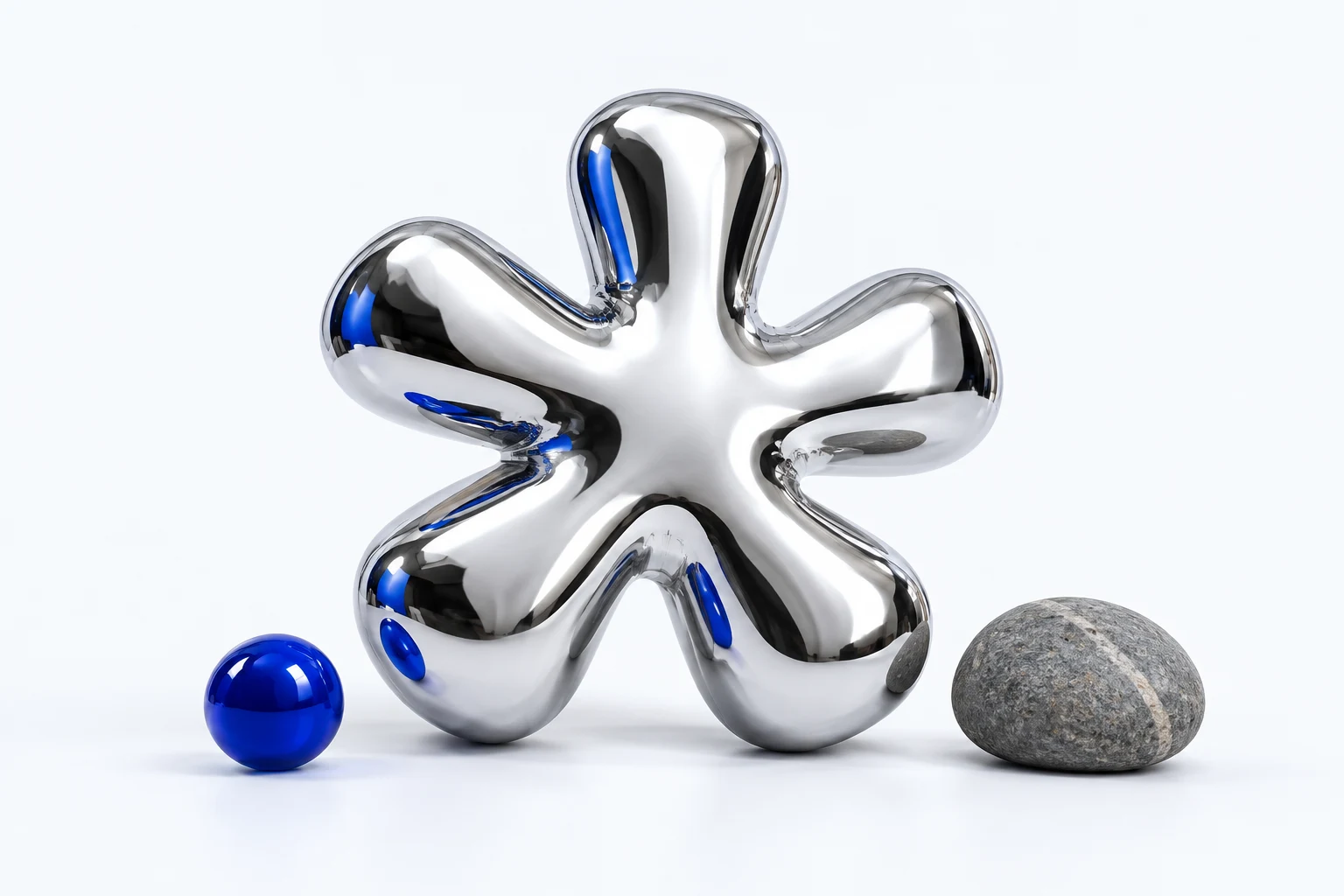 A shiny, six-lobed chrome toy next to a blue ball and an ordinary stone